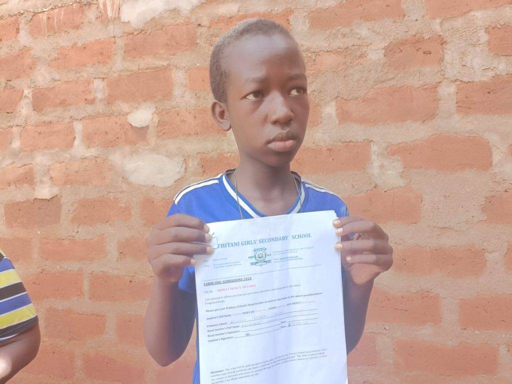 Mercy Muloko displaying her admission letter to Thitani Girls High School. She has not joined the school due to lack of school fees. Photo: Linah Musangi/TV47